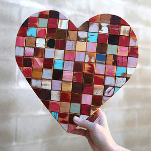 Hand holding a heart made of colorful wooden mosaic cubes