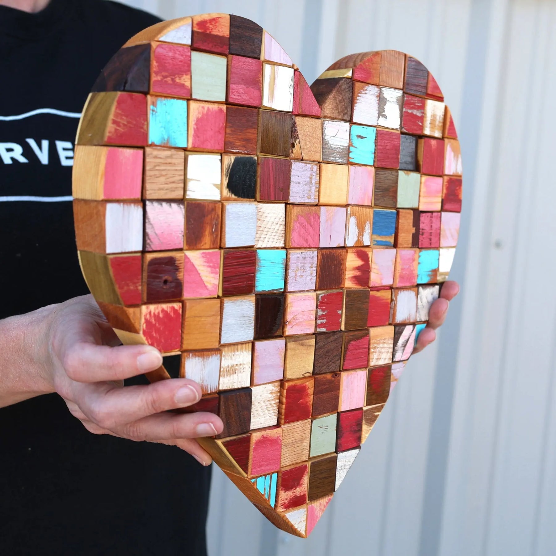 Heart-shaped mosaic art made from reclaimed wooden cubes in various colors.