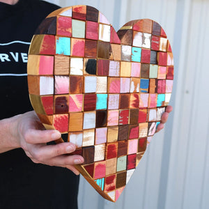 Heart-shaped mosaic art made from reclaimed wooden cubes in various colors.