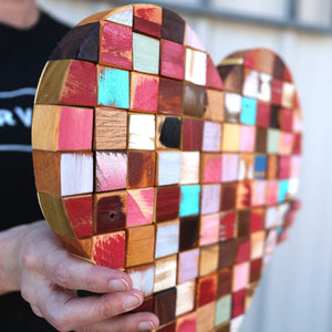 Heart-shaped mosaic wall art made of colorful reclaimed wood cubes.