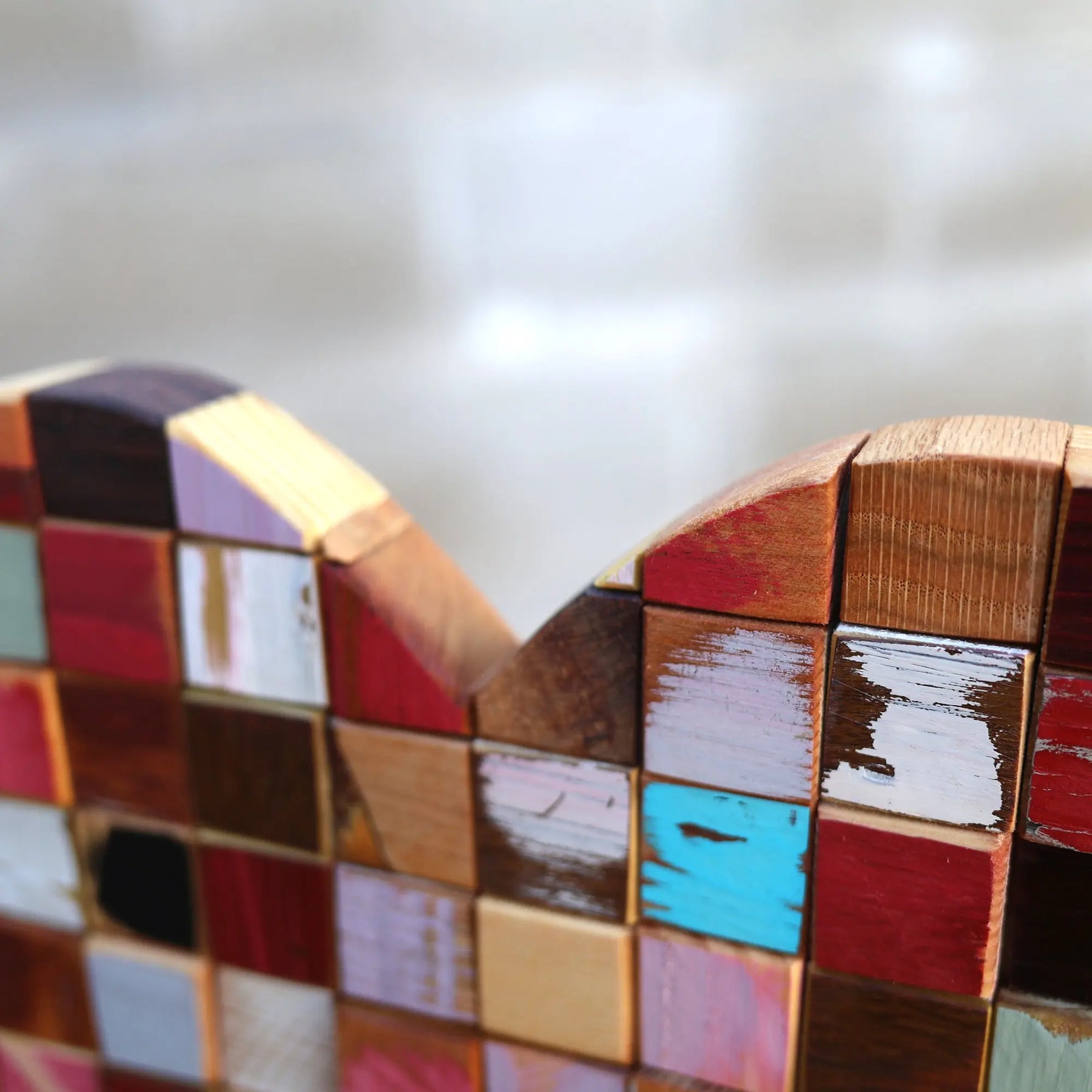 Close-up of a mosaic heart made of colorful, reclaimed wooden cubes.