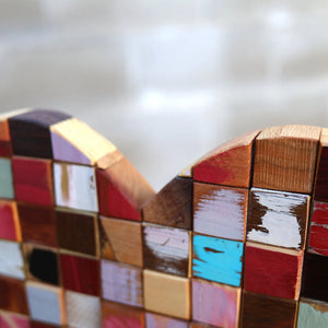 Close-up of a mosaic heart made of colorful, reclaimed wooden cubes.