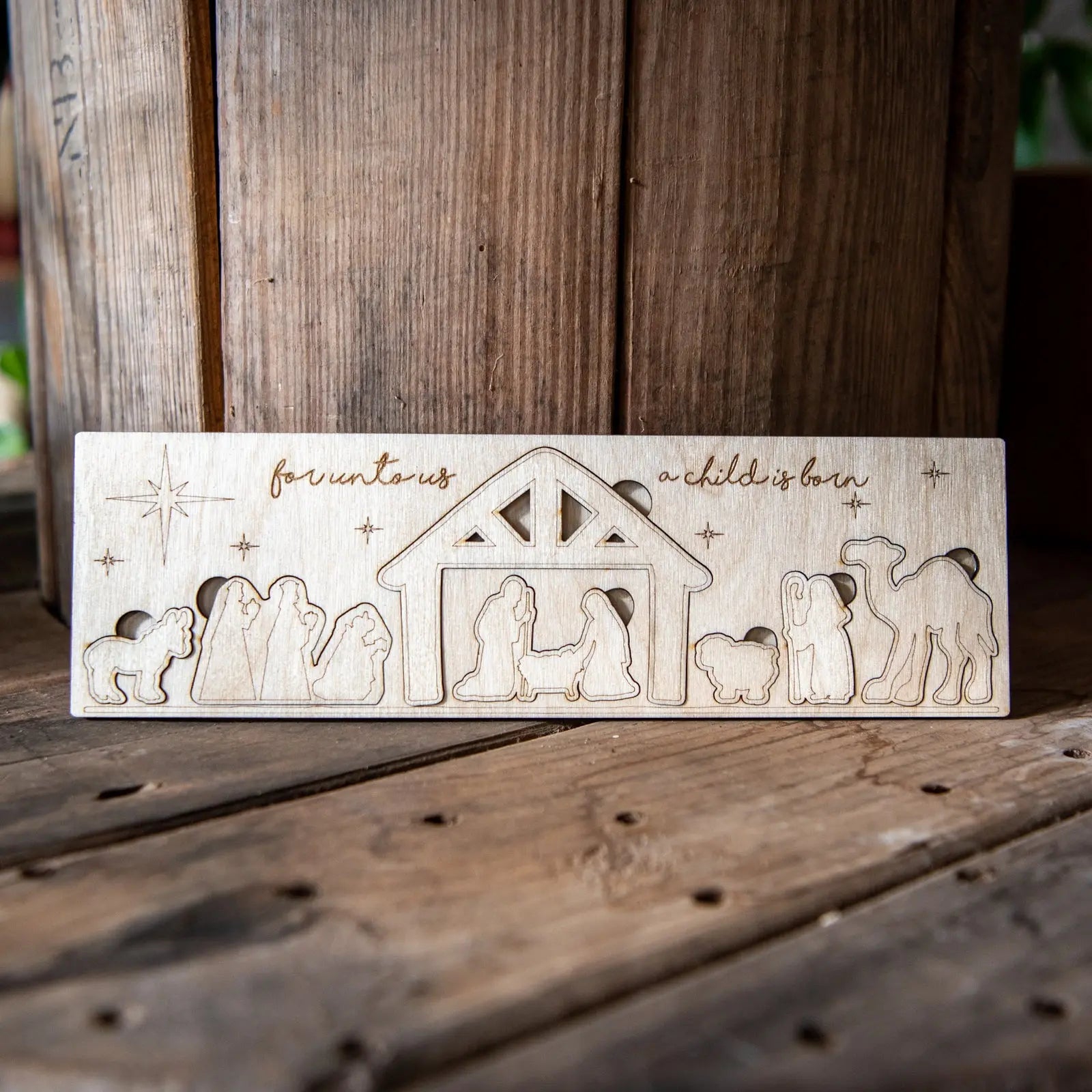 Wooden nativity scene puzzle with figures and text on a rustic surface