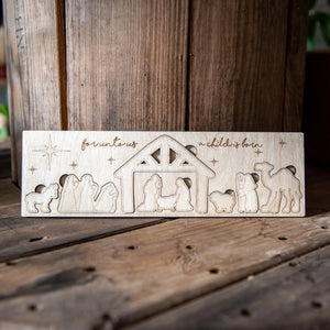 Wooden nativity scene puzzle with figures and text on a rustic surface