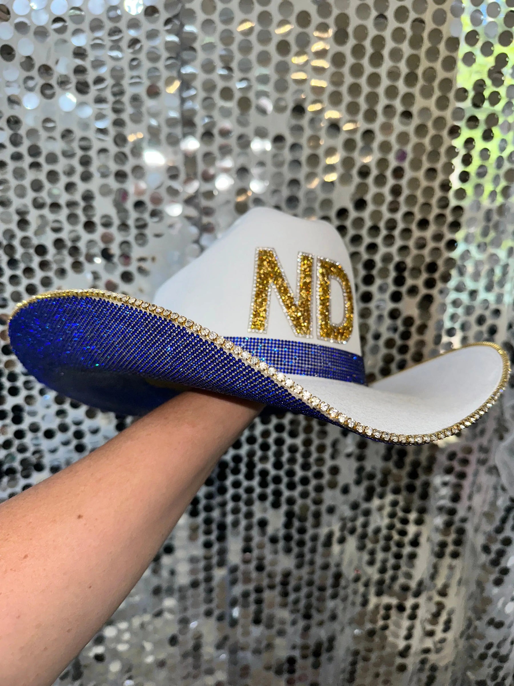 White straw cowboy hat with blue rhinestones, gold ND letters, and rhinestone trim