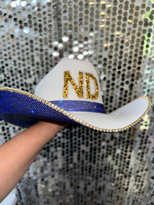 White straw Notre Dame cowboy hat with blue rhinestones and gold "ND" letters.