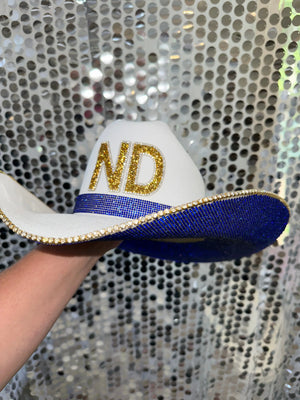 White cowgirl hat with blue and gold rhinestones and ND letters