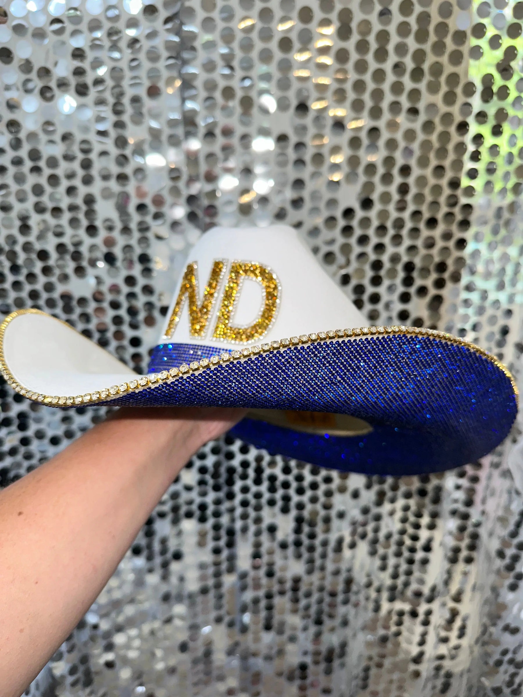 White cowboy hat with blue rhinestones and gold letters