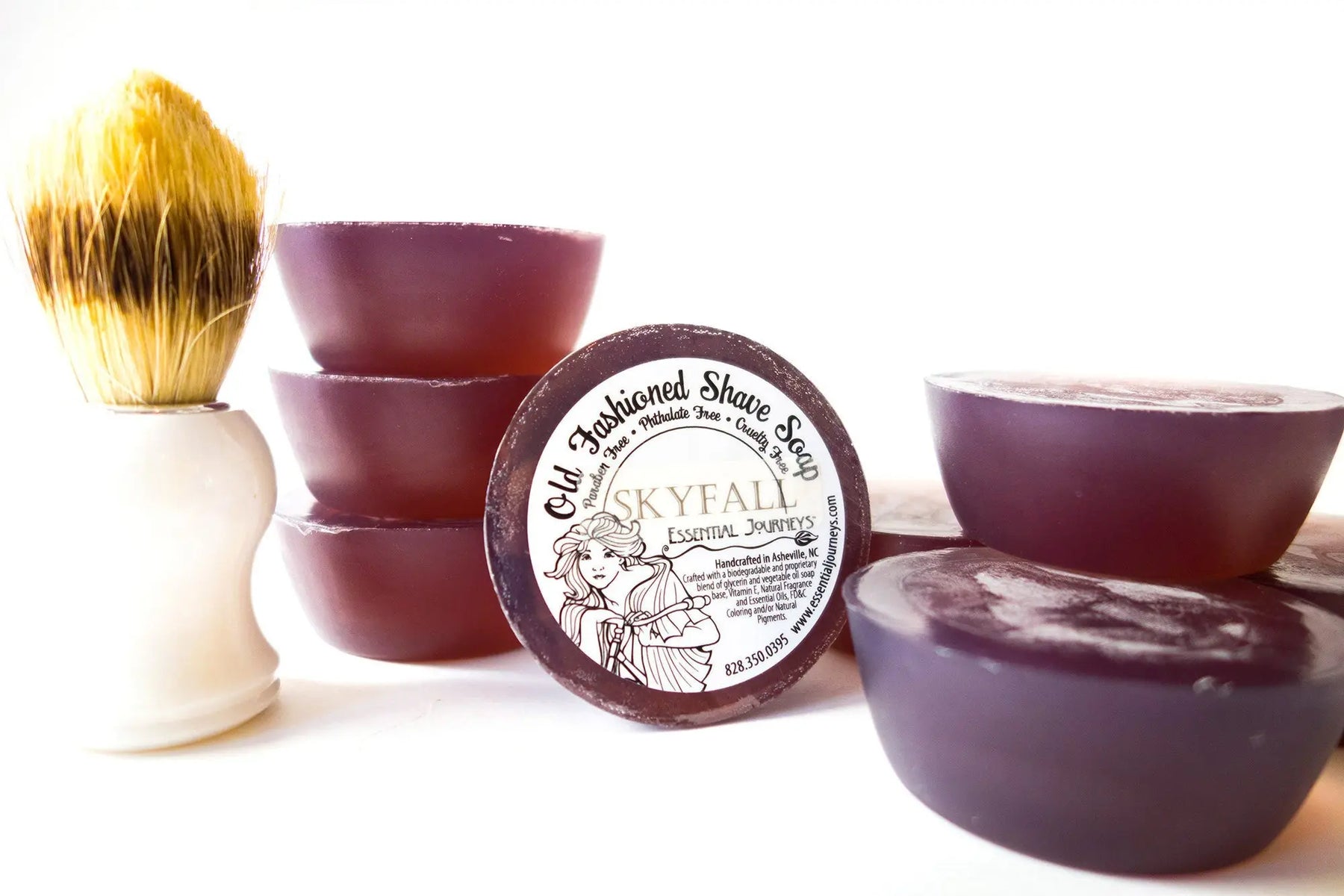 Purple round shave soap bars and a white handle brush with yellow and brown bristles.