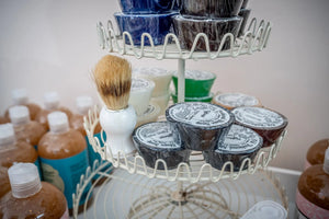 Essential Journeys Old Fashioned Men's Shave Soap collection on a white tiered display.