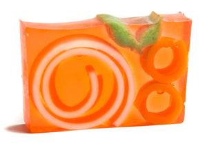 Orange swirl soap slice with green leaves and orange rings embedded in transparent soap