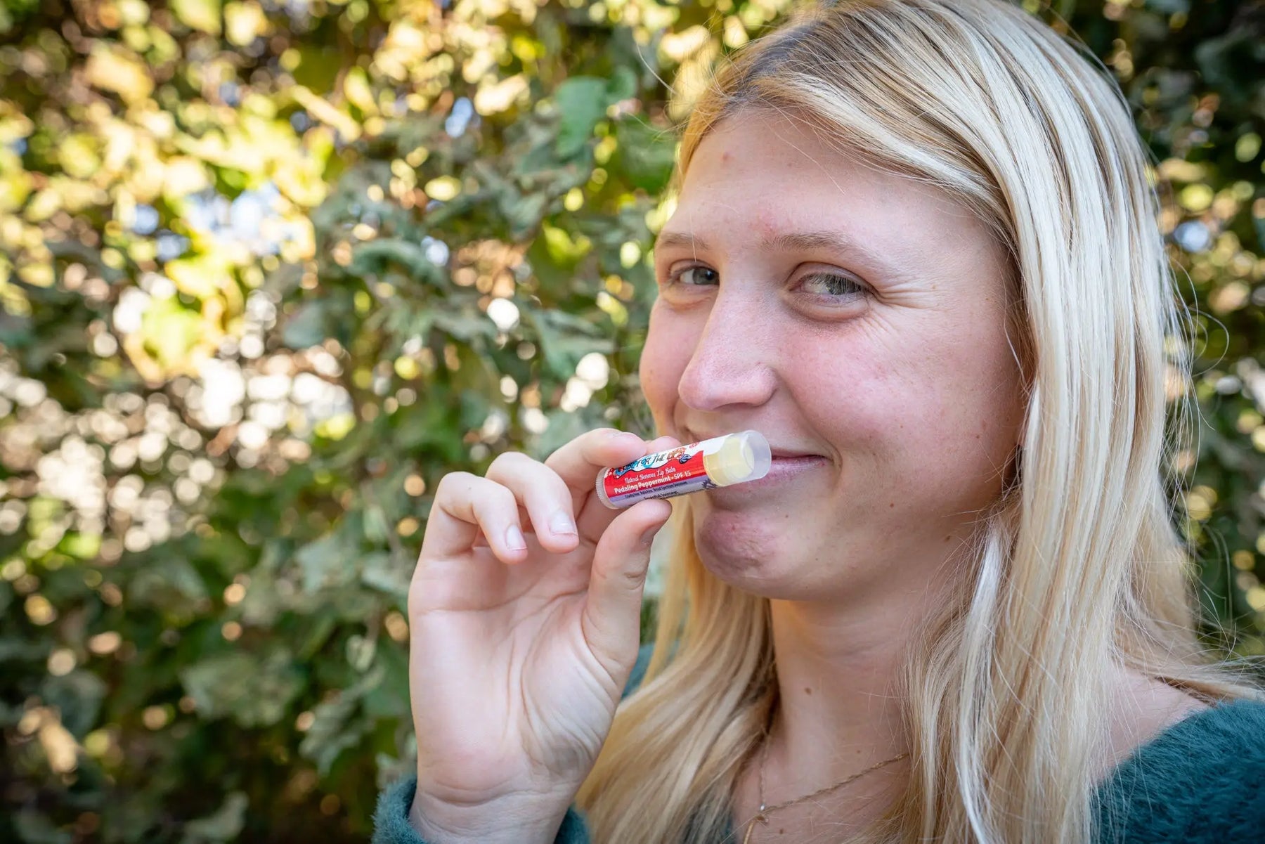 Woman applying PEDALING PEPPERMINT SPF 15 lip balm.