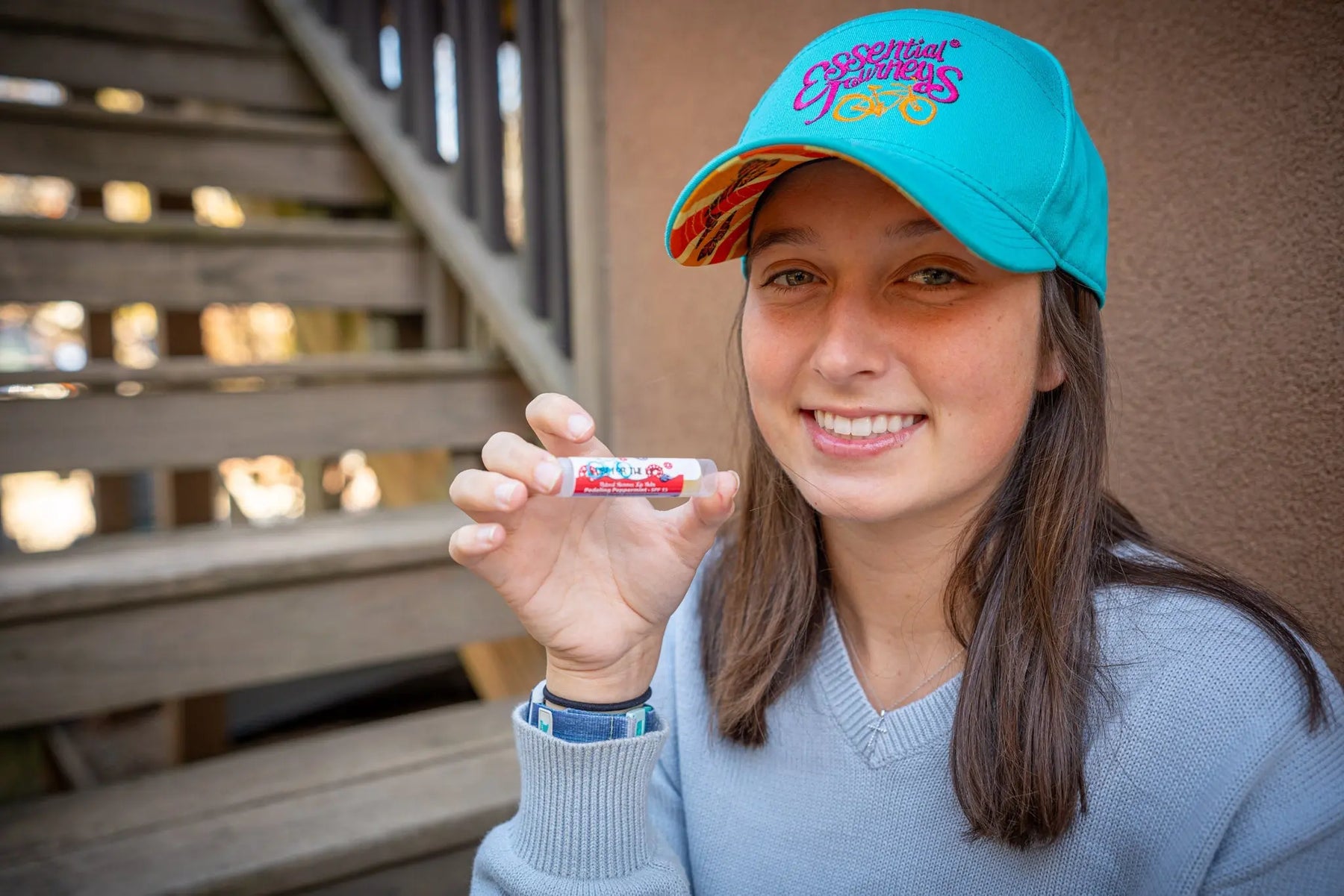 Woman in a blue hat holding a tube of lip balm with SPF 15