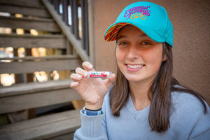Woman in a blue hat holding a tube of lip balm with SPF 15