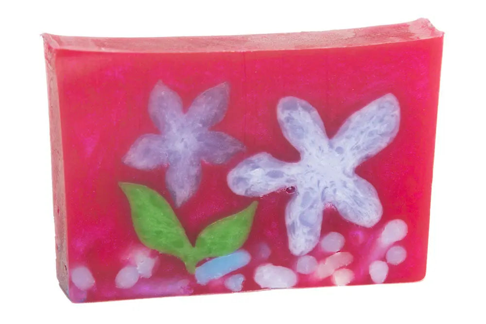 Pink soap slice with embedded purple flowers and green leaves.