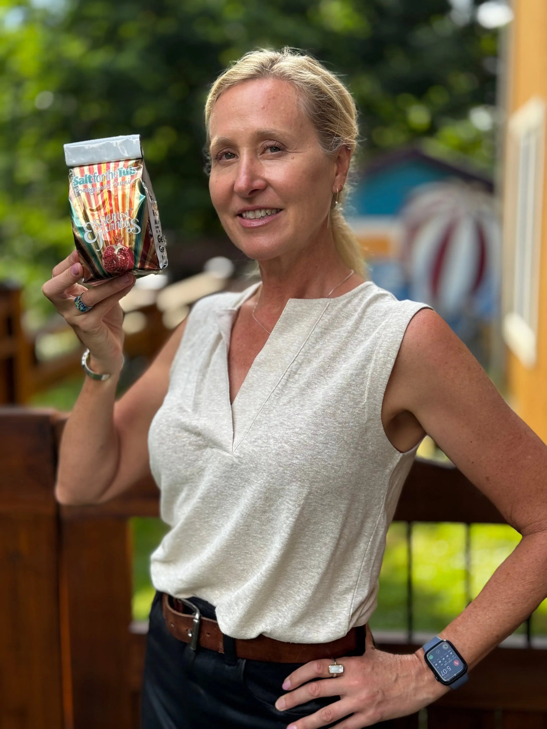 Woman holding Pomegranate Sunrise Arnica Bath Salts product from Essential Journeys.