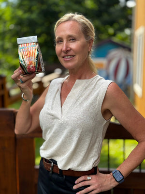 Woman holding Pomegranate Sunrise Arnica Bath Salts product from Essential Journeys.
