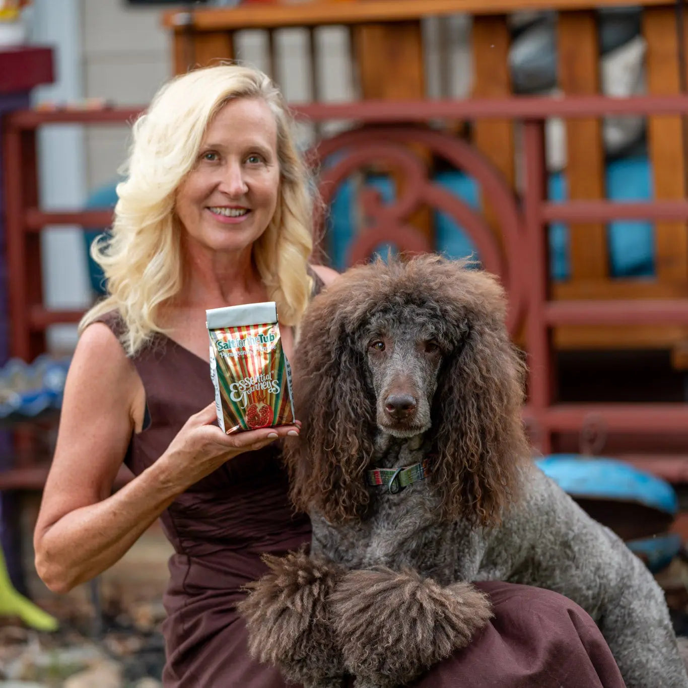 Woman holding Pomegranate Sunrise Arnica Bath Salts next to a poodle.