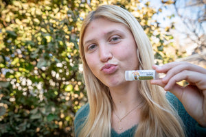Woman holding a tube of "The Appalachian Goat" lip balm with "GOAT" visible.
