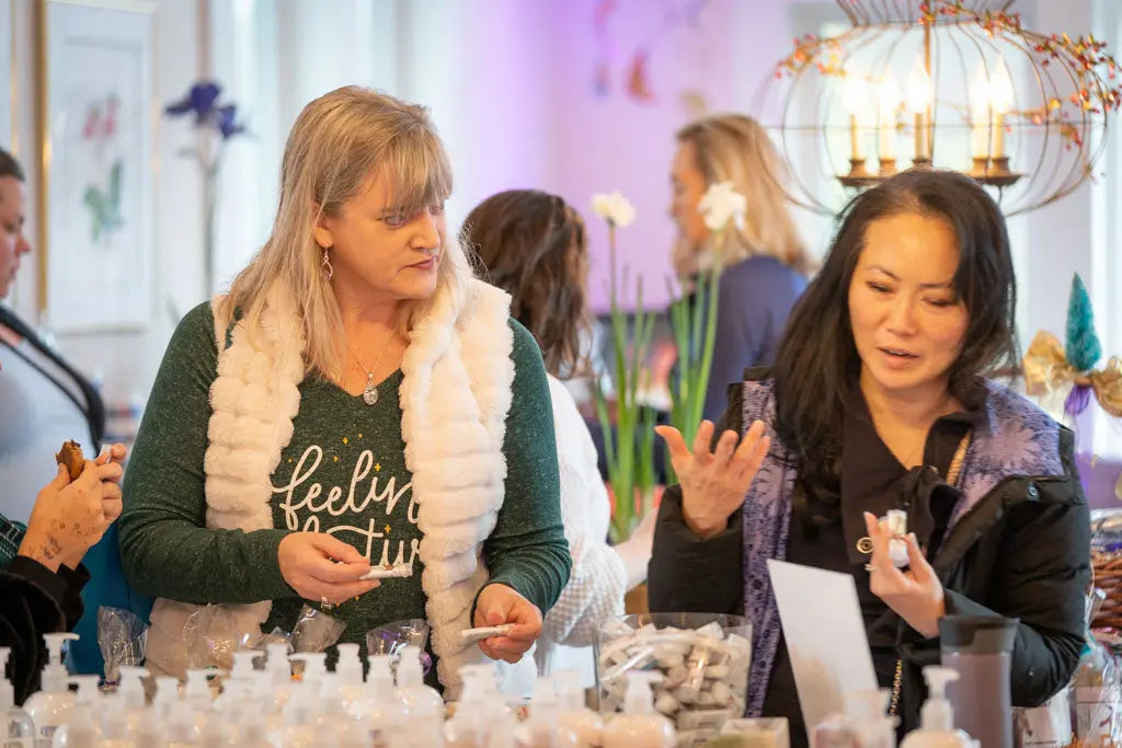 Women examining products on a display table.