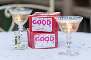 Pink Prosecco soaps and lip balms on a white surface with champagne glasses.