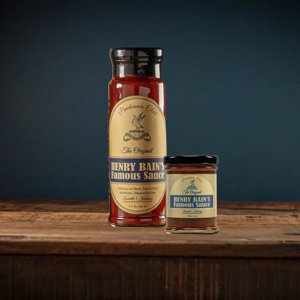 Two bottles of Henry Bain's Famous Sauce by Pendennis Club on a wooden surface.