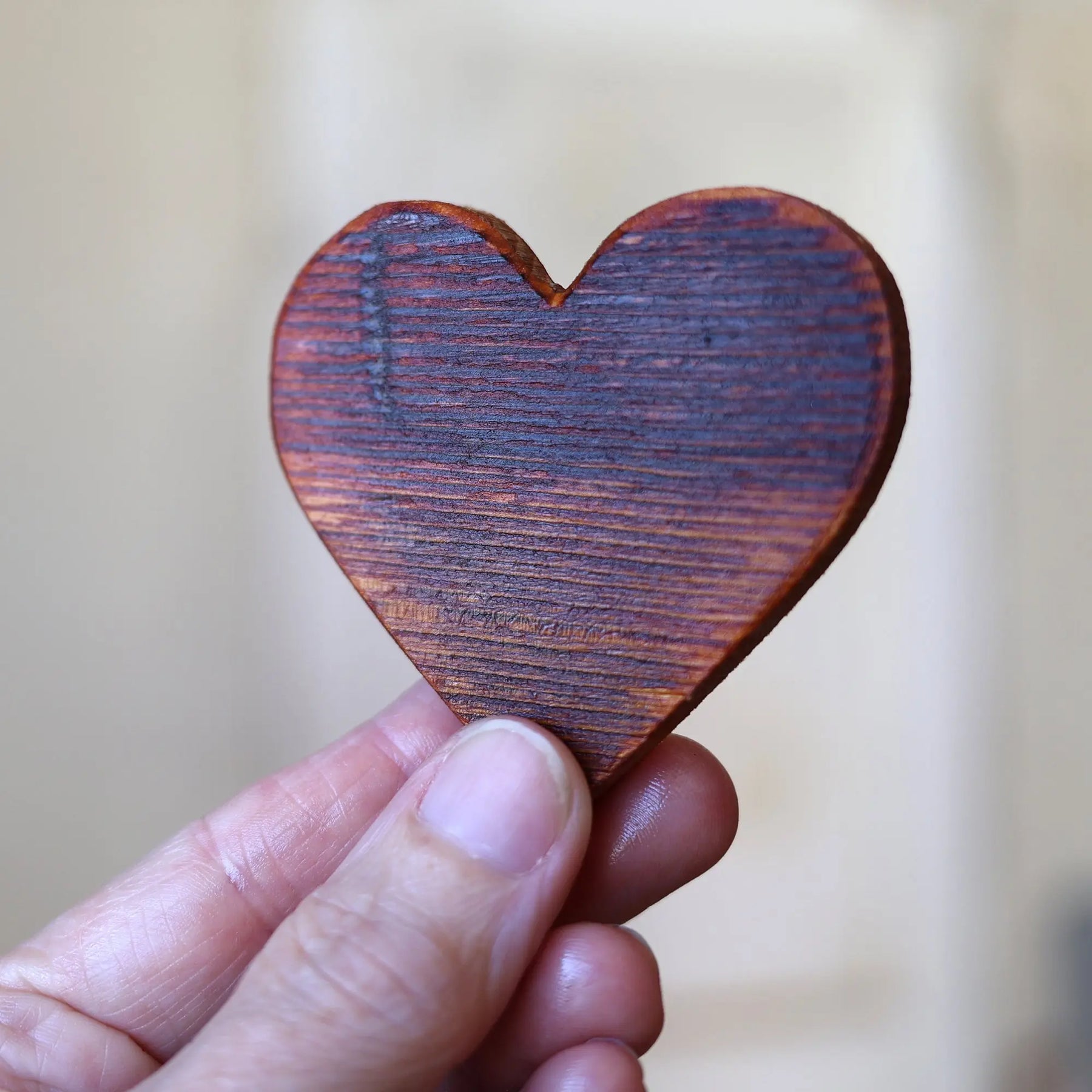 Wooden heart shape held in a hand, made from reclaimed piano soundboard.