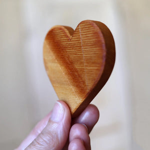 Wooden heart held by fingers against a light background