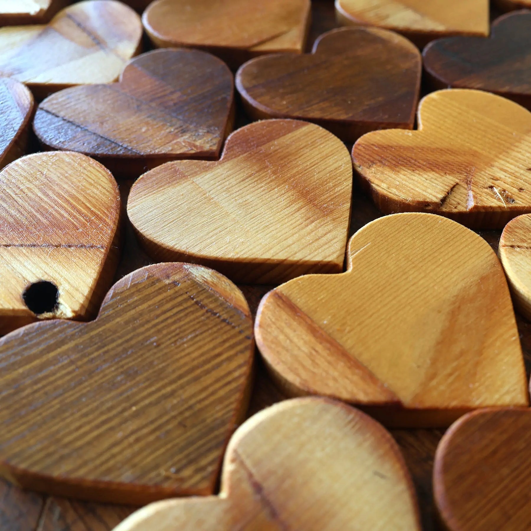 Collection of reclaimed wooden hearts with varying grain patterns and shades.