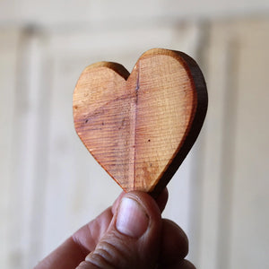 Reclaimed wood heart held in hand, rustic texture and natural grain.