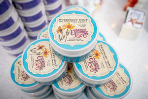 Rosemary Mint Arnica Salve jars from Essential Journeys with floral illustrations.