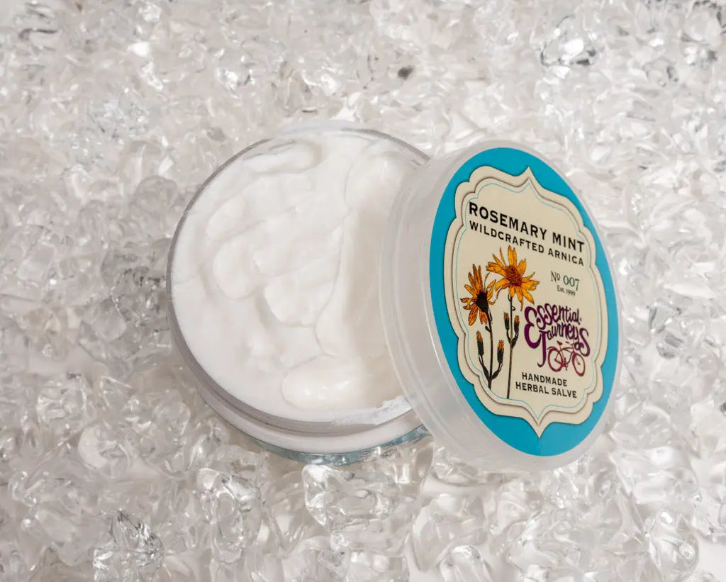 Essential Journeys Rosemary Mint Arnica Salve in clear jar with blue label on ice.