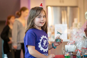 Young girl holding a wrapped rubber duck soap cupcake with a mini Santa hat.