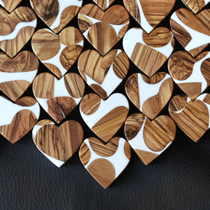 Heart shapes made of olive wood and white resin with natural grain patterns.