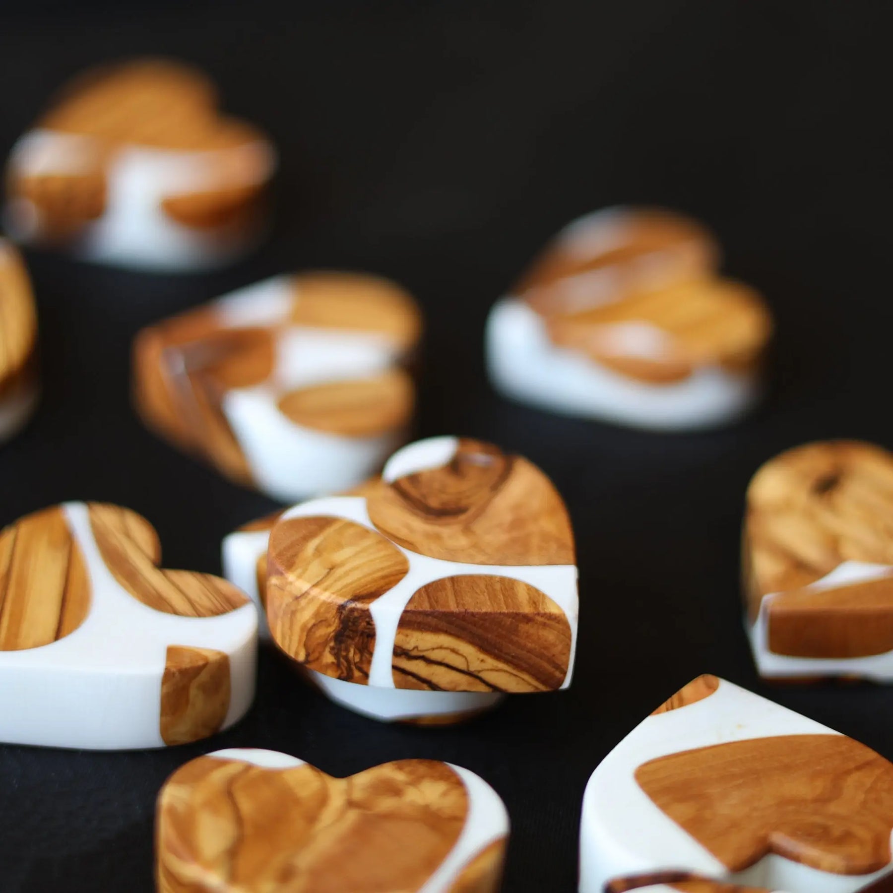 Heart-shaped objects made of olive wood and white resin in a marbled pattern.
