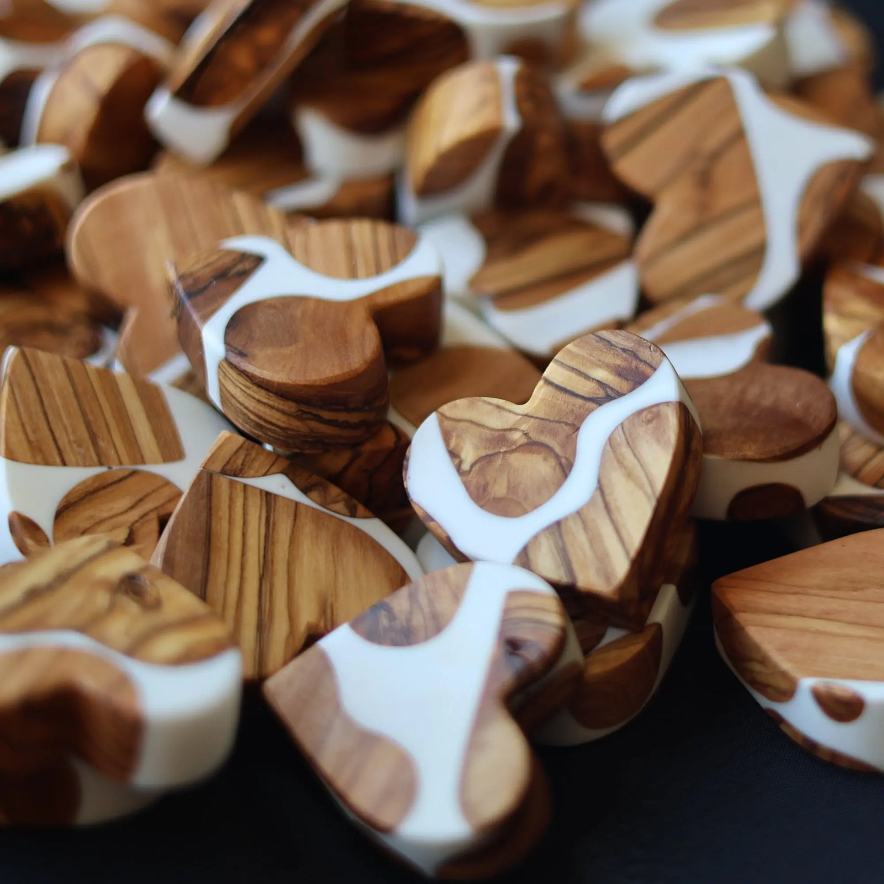Wooden heart shapes with white resin inlay on black background