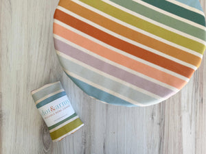 Reusable bowl cover with beach chair stripes on a wooden table.