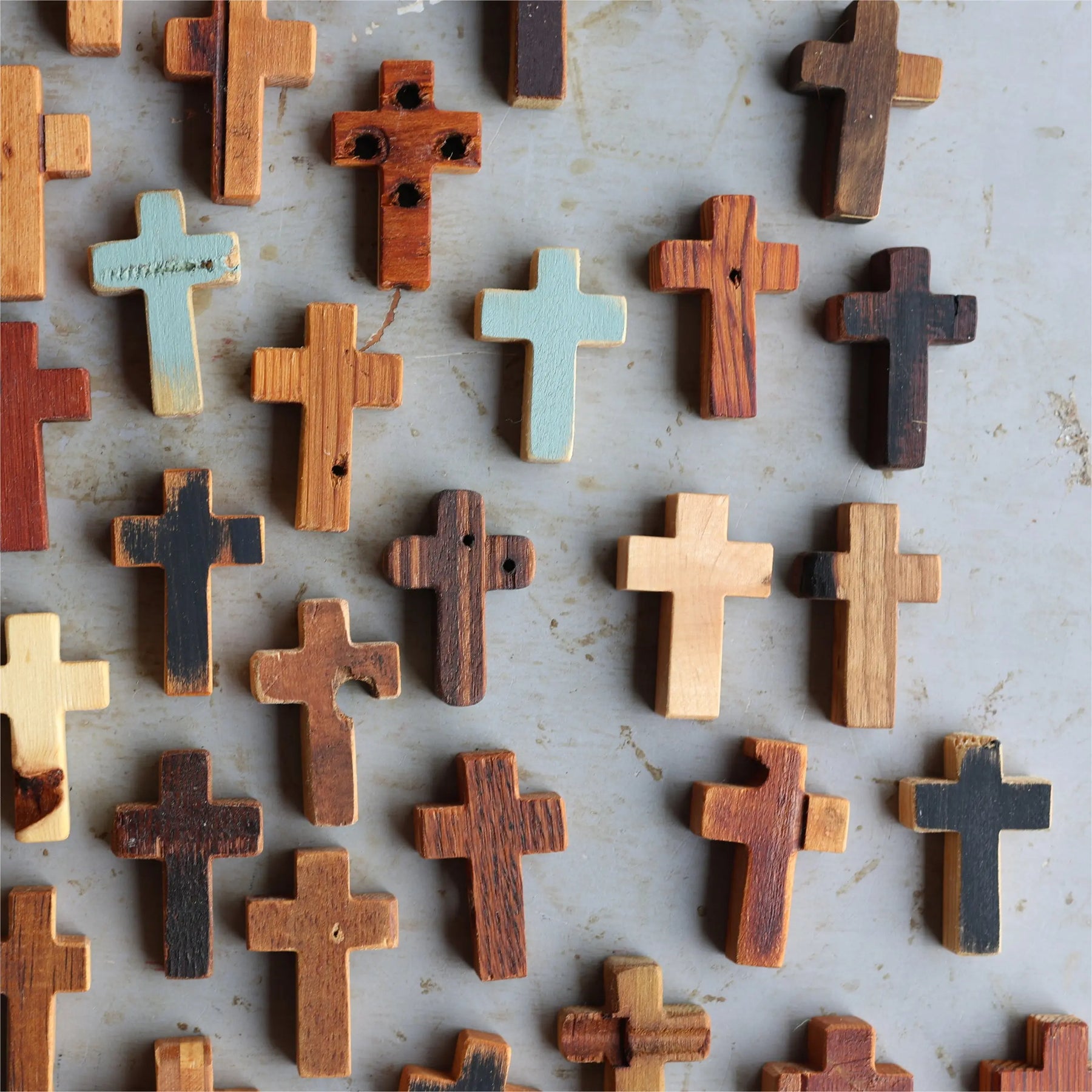 Assortment of wooden pocket crosses in various natural wood tones and finishes.