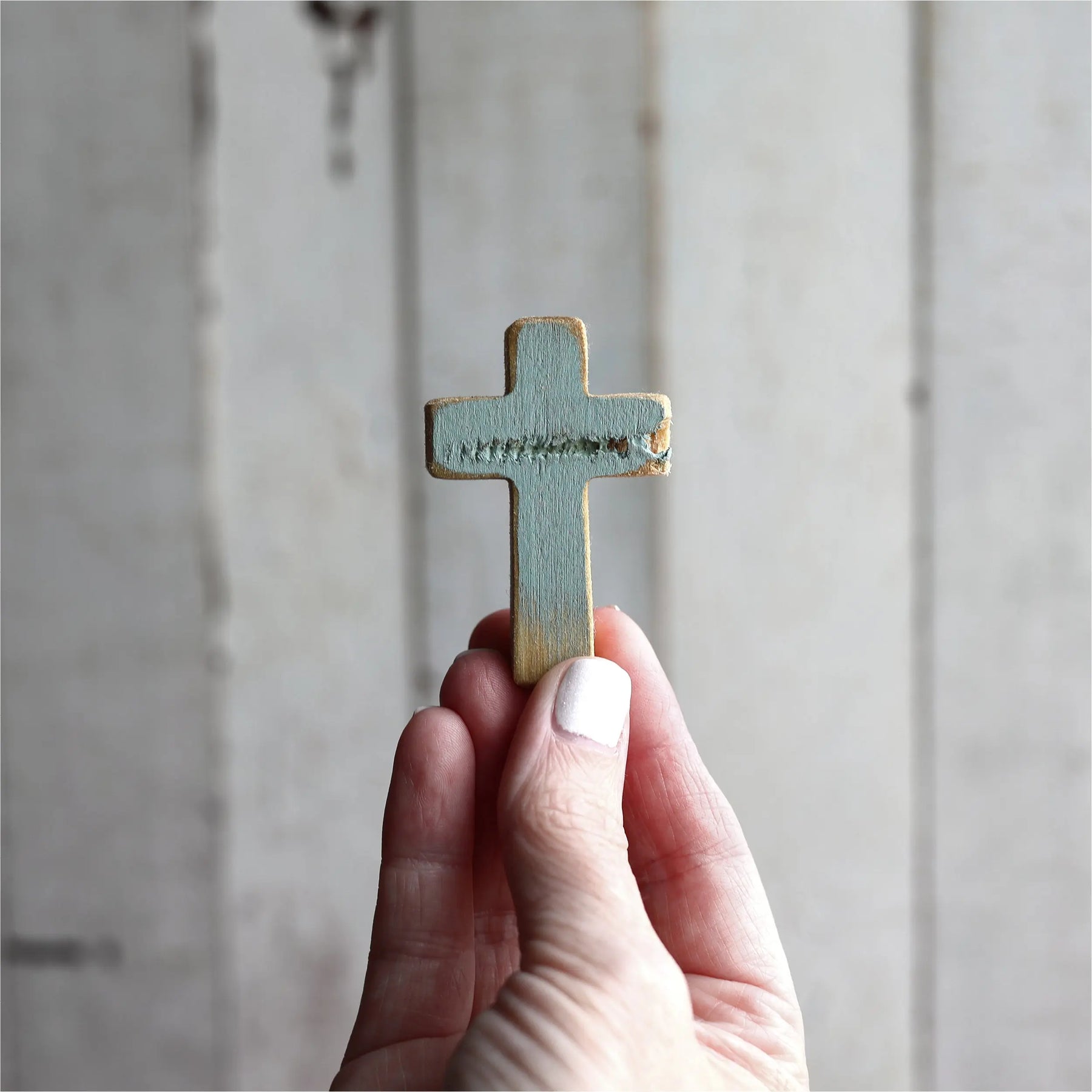 Small blue rugged pocket cross held in a hand