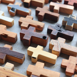 Multiple wooden pocket crosses with varied wood grains and textures arranged closely.