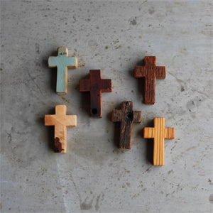 Six wooden pocket crosses with varied textures and finishes on a textured surface.