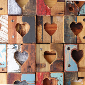 Rustic reclaimed wood tiles with carved heart shapes arranged in a grid.