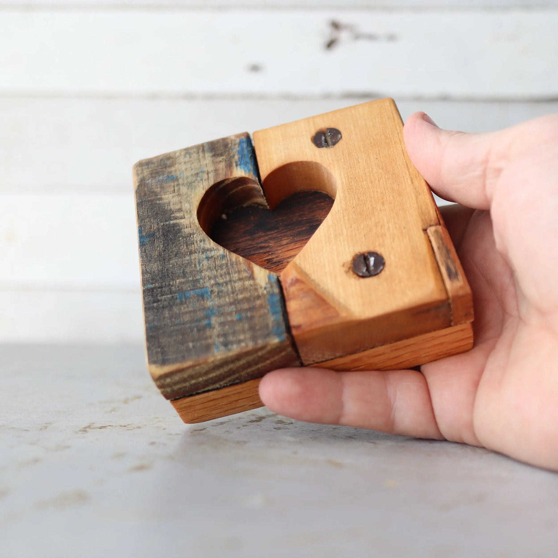 Hand holding a wooden heart tile with a carved heart shape