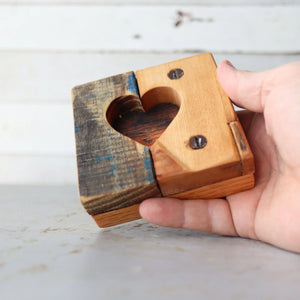 Hand holding a wooden heart tile with a carved heart shape