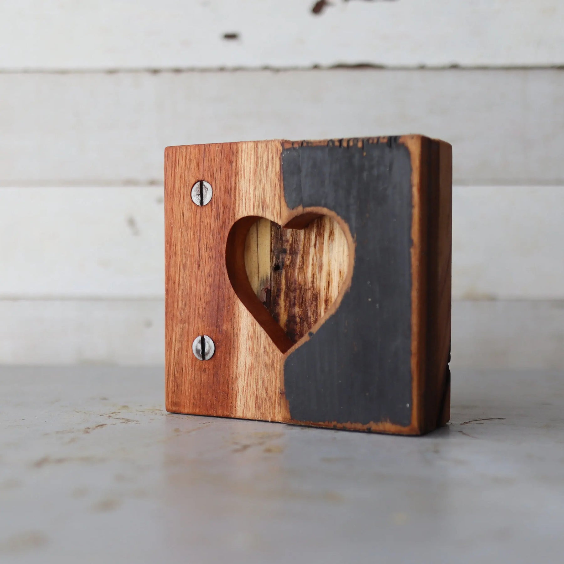 Wooden block with a heart cut-out, half natural wood and half dark gray painted