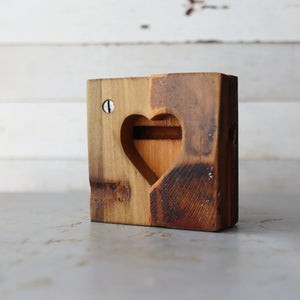 Wooden heart cutout with a screw on the left side against a white background.