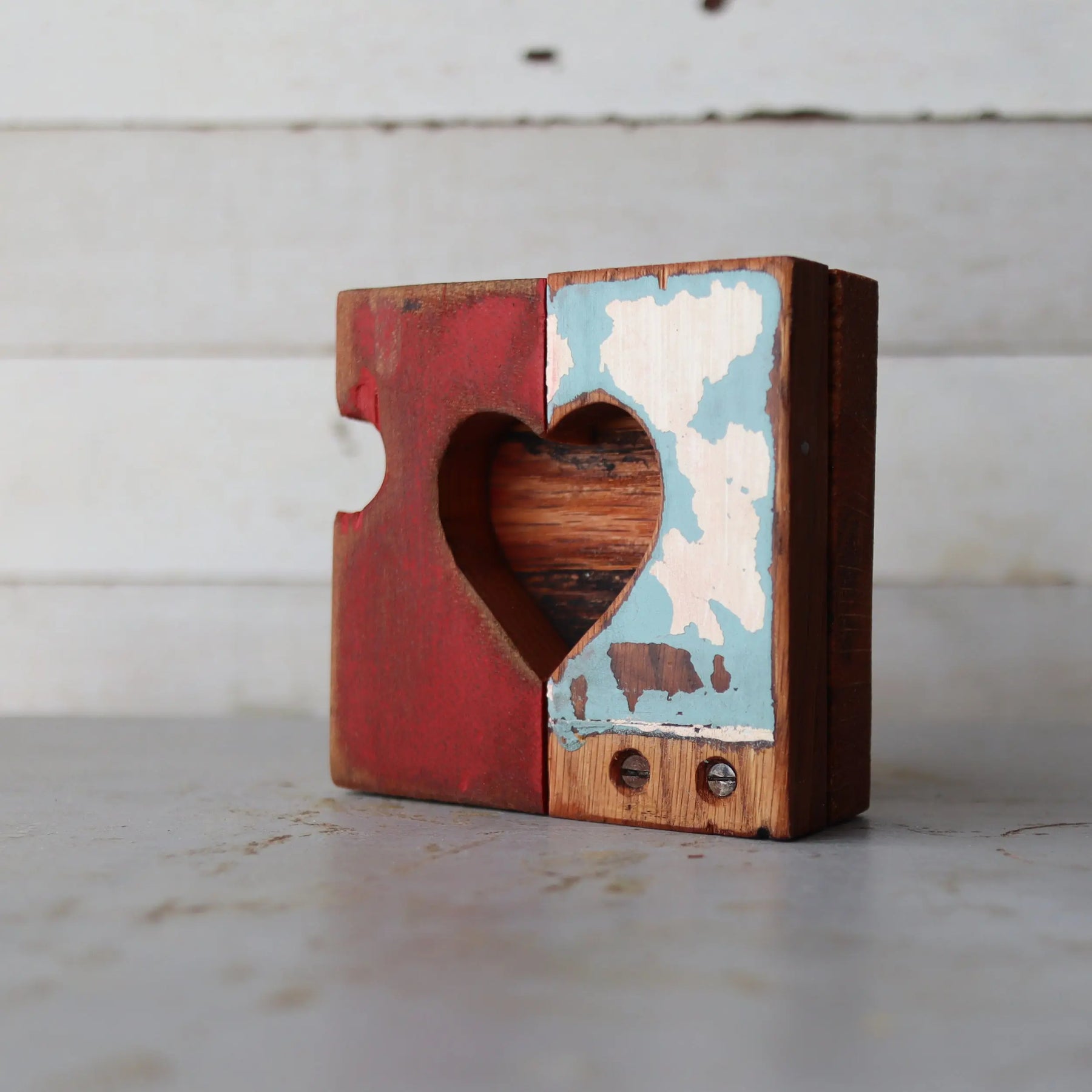 Wooden heart object with a heart cutout, red on one side and distressed blue/white on the other.
