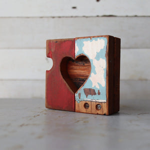 Wooden heart object with a heart cutout, red on one side and distressed blue/white on the other.