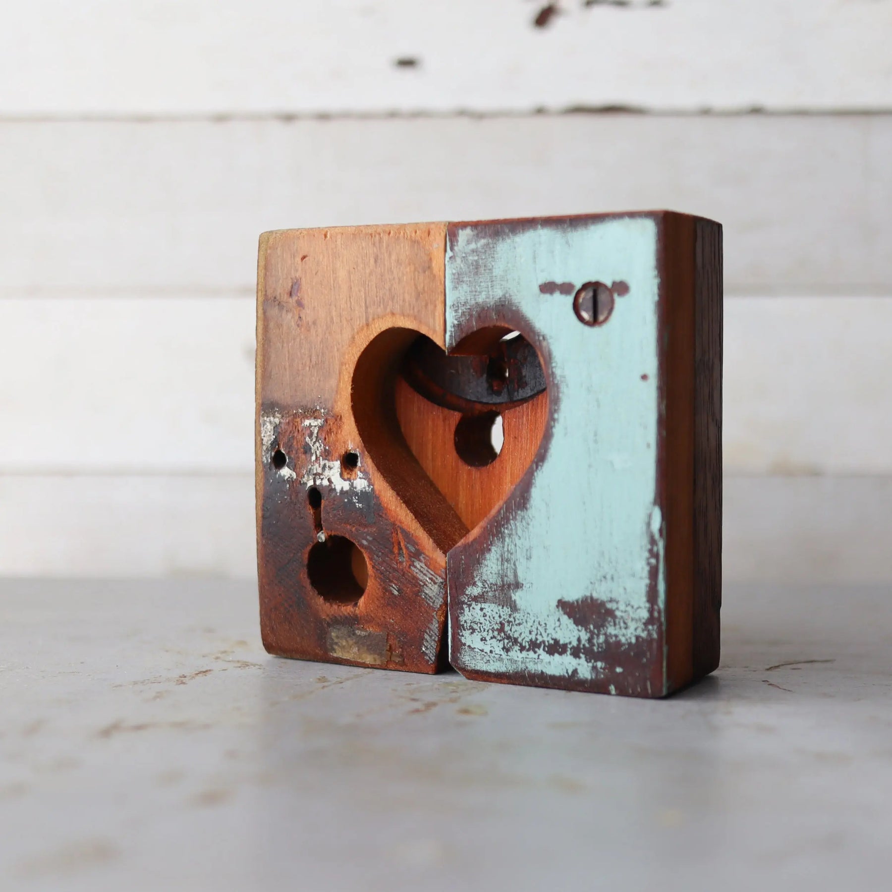 Two wooden blocks with a heart shape cut out, one painted teal, one natural wood.