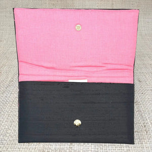 Black clutch with pink lining and gold snap closure